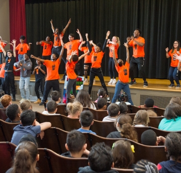 Students on stage raising their arms