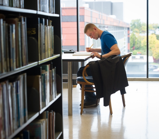 Student at work table in Buffalo State E.H. Butler Library book stacks