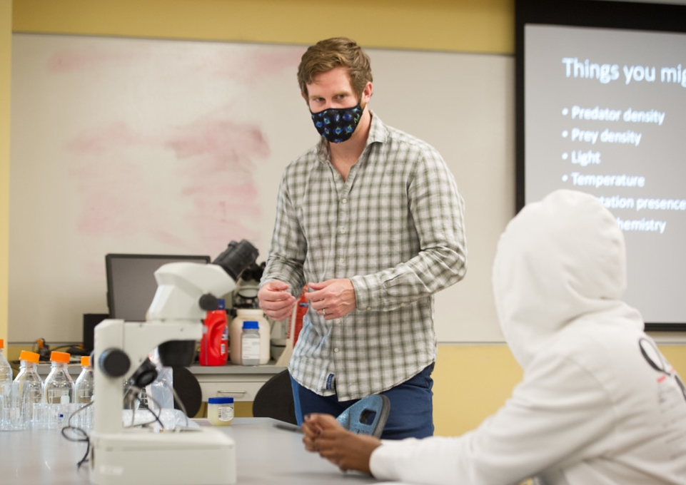Gavin Leighton speaks to a seated student in BIO 213